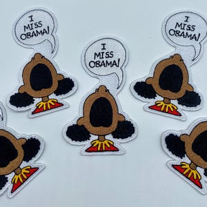 May include: Five embroidered iron-on patches featuring a cartoon character with an open mouth and the text "I Miss Obama!" above the character.