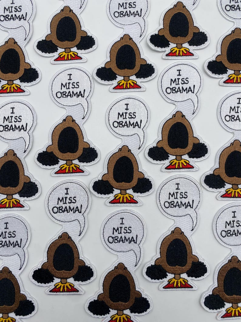 May include: A collection of embroidered patches featuring a cartoon character with the text "I Miss Obama!" in a speech bubble. The patches are white with black outlines and feature a brown character with black hair and a red shirt.