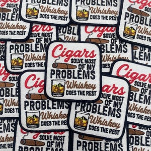 May include: Embroidered patches with the text "Cigars solve most of my problems, Whiskey does the rest." Each patch features a cigar and a glass of whiskey. The patches have a white background with black and red text.