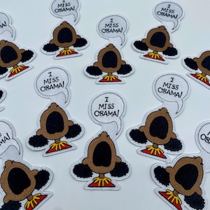 May include: A set of 10 iron-on patches featuring a cartoon character with the text "I Miss Obama!" in a speech bubble. The character is a brown-skinned person with black hair and a large open mouth.