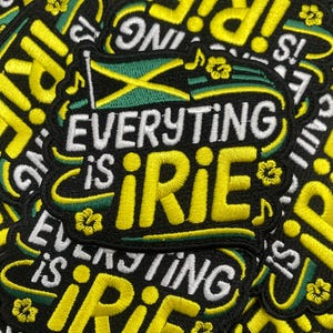 Peut inclure: Écusson brodé avec l'inscription "Everything is Irie" en jaune et blanc sur fond noir. Le patch présente un drapeau jamaïcain et des motifs floraux, évoquant une ambiance détendue et positive.