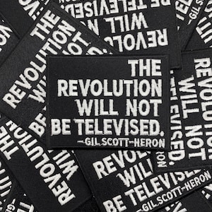 May include: A collection of rectangular black embroidered patches featuring the white text THE REVOLUTION WILL NOT BE TELEVISED and the name GIL SCOTT-HERON. The patches are arranged in an overlapping pattern, displaying the same bold design.