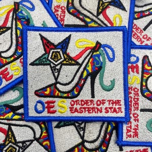 Puede incluir: Parches bordados con borde azul y fondo gris claro. Los parches presentan un diseño de zapato de tacón alto y estrella, con el texto "OES ORDER OF THE EASTERN STAR" en amarillo y rojo.