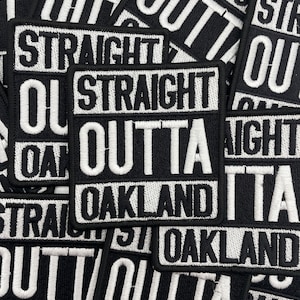 May include: Black and white embroidered patches with the text "STRAIGHT OUTTA OAKLAND". The patches are rectangular with a black background and white lettering. The patches are stacked on top of each other.
