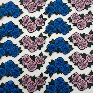 May include: Embroidered patches featuring clusters of roses in blue and pink. Each patch has a black outline and green leaves. The patches are arranged on a white background, creating a pattern.