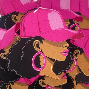 Puede incluir: Un conjunto de parches bordados en rosa y negro que representan a una mujer con una gorra de béisbol rosa y grandes pendientes de aro. La mujer tiene la piel morena y el pelo negro rizado.