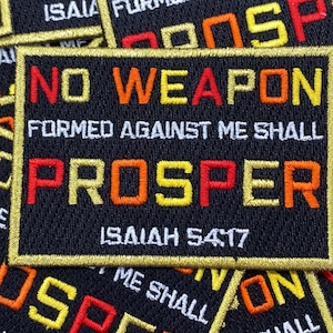 May include: A black patch with gold trim features the text "No weapon formed against me shall prosper" in red, orange, and yellow lettering. The text "Isaiah 54:17" is also included in white lettering.