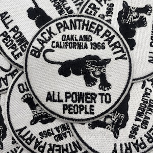 Op de afbeelding: Geborduurde patches met de woorden "Black Panther Party" en "Oakland California 1966" in zwart op een witte achtergrond. Een zwarte panter staat in het midden, met daaronder de woorden "All Power to People".