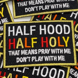 May include: Black embroidered patch with gold trim. The patch reads "Half Hood Half Holy" in white text with the words "That means pray with me Don't play with me" in smaller white text.