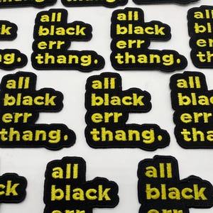 以下が含まれることがあります： 「all black err thang.」と黄色い刺繍で書かれた黒い布のパッチがいくつかあるクローズアップ