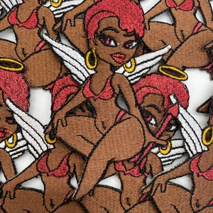 Puede incluir: Un conjunto de parches bordados para planchar que representan a un personaje de dibujos animados con cabello rojo, piel morena y alas de ángel. El personaje lleva un bikini rojo y un halo.