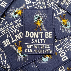 May include: Navy blue embroidered patches with the text "DON'T BE SALTY" and an illustration of a person under an umbrella. Each patch has a net weight of 26 oz (1 lb, 10 oz) or 737g.