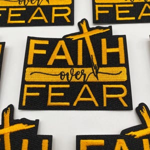 May include: Five black embroidered patches with yellow stitching. Each patch features a cross and the text "Faith over Fear".