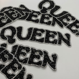 Pode incluir: Três patches de strass pretos que soletram a palavra "QUEEN" em uma fonte estilizada. Os patches estão em um fundo branco.