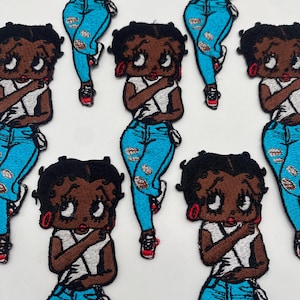 Puede incluir: Ocho parches bordados para planchar que representan a un personaje de dibujos animados con piel morena, camisa blanca, pantalones vaqueros azules y zapatos rojos. El personaje tiene ojos grandes, labios rojos y cabello castaño.