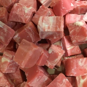 Pode incluir: Um close-up de fudge rosa e branco cortado em pequenos quadrados. O fudge tem uma aparência marmorizada.