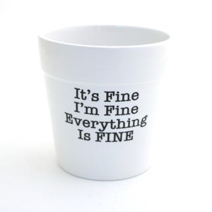 May include: A white ceramic plant pot featuring the black printed text It's Fine I'm Fine Everything Is FINE. The container has a smooth finish, a wide circular opening, and a tapered cylindrical shape with a flat base for stable placement.