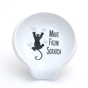 May include: White ceramic spoon rest with a black cat illustration and the text "Made From Scratch".