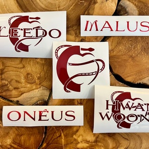 Puede incluir: Cinco pegatinas de vinilo blanco con letras rojas y un dise&ntilde;o de serpiente roja. Las pegatinas dicen "LEEDO", "MALUS", "ONEUS", "HWAN WOONG" y una serpiente envuelta alrededor de un coraz&oacute;n.