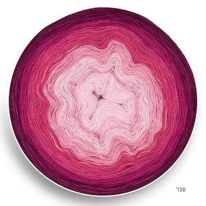 Può includere: Un gomitolo di lana circolare con una sfumatura di colore, che passa dal magenta intenso al rosa chiaro al centro. Il filato è ben avvolto, creando una superficie strutturata. Il numero '138' è visibile nell'angolo in basso a destra.