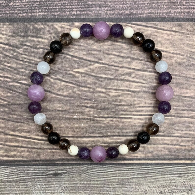 May include: A purple, white and black beaded bracelet with a variety of gemstone beads.