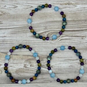 Puede incluir: Tres pulseras de cuentas con una variedad de colores, incluyendo azul, verde, morado y blanco. Las pulseras est&aacute;n hechas de cuentas redondas y est&aacute;n dispuestas en c&iacute;rculo.