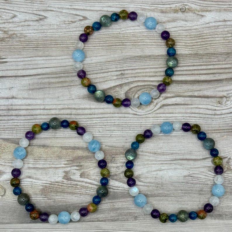 Puede incluir: Tres pulseras de cuentas con una variedad de colores, incluyendo azul, verde, morado y blanco. Las pulseras est&aacute;n hechas de cuentas redondas y est&aacute;n dispuestas en c&iacute;rculo.
