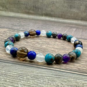 May include: A beaded bracelet featuring a range of gemstones, including turquoise, amethyst, lapis lazuli, and smoky quartz.