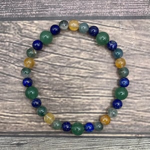 May include: A bracelet made of blue, green, and yellow beads. The beads are round and have a smooth, polished finish.
