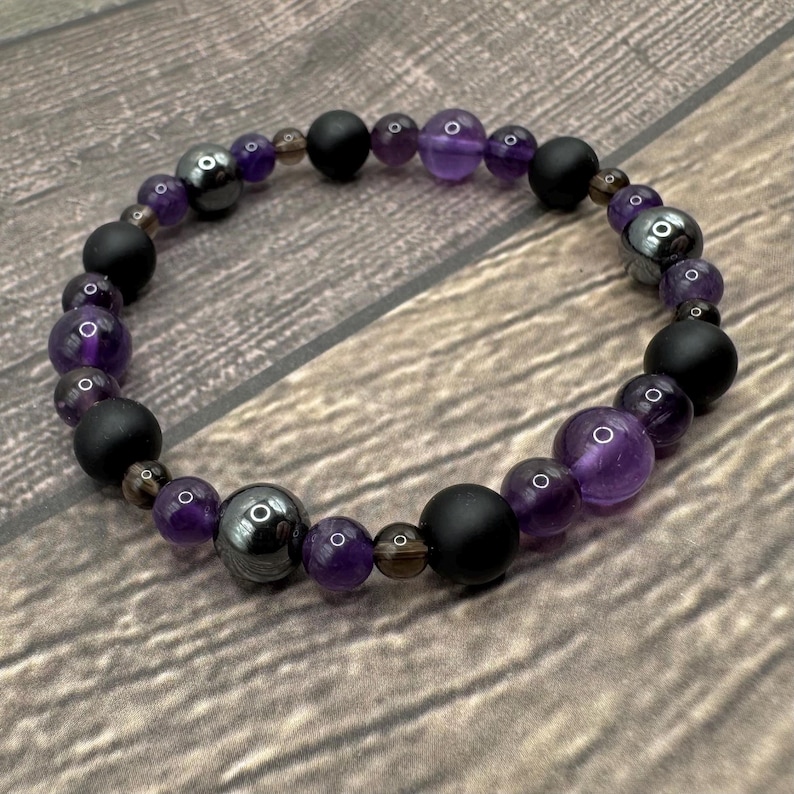 May include: A purple amethyst, black onyx, and hematite beaded bracelet. The bracelet is made with natural stones and is designed to be worn on the wrist.