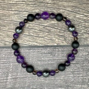 May include: A purple and black beaded bracelet with amethyst, hematite, and black onyx beads.