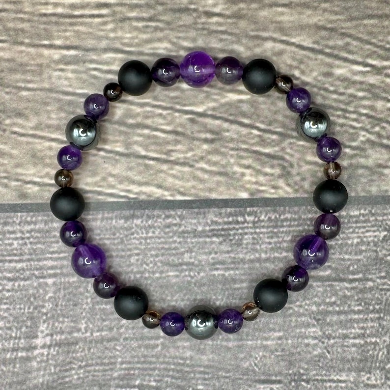 May include: A purple and black beaded bracelet with amethyst, hematite, and black onyx beads.