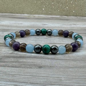 Pode incluir: Um bracelete de contas com contas alternadas de ametista, quartzo fumado, &aacute;gua-marinha, malaquita e hematita.