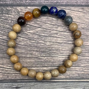 May include: A wooden beaded bracelet with a variety of gemstone beads, including tiger's eye, lapis lazuli, and carnelian.