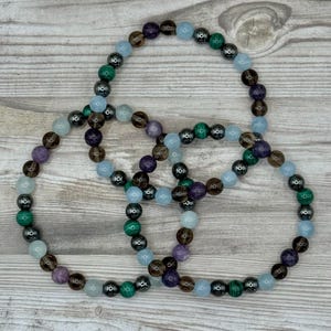 Pode incluir: Tr&ecirc;s pulseiras de contas com contas alternadas de ametista, quartzo fumado, &aacute;gua-marinha, hematita e malaquita.