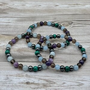 Pode incluir: Tr&ecirc;s pulseiras de contas com pedras de v&aacute;rias cores, incluindo ametista, &aacute;gua-marinha, quartzo fumado, malaquita e hematita.