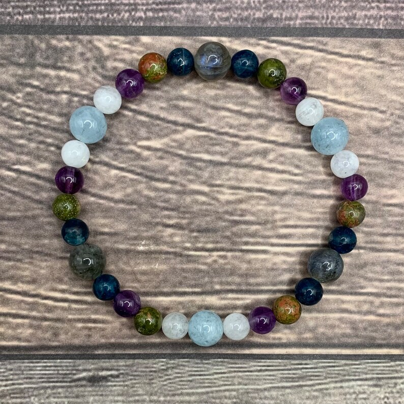 Puede incluir: Un brazalete de cuentas con una variedad de colores, incluyendo azul, verde, morado y blanco. Las cuentas son redondas y tienen un acabado liso y pulido.