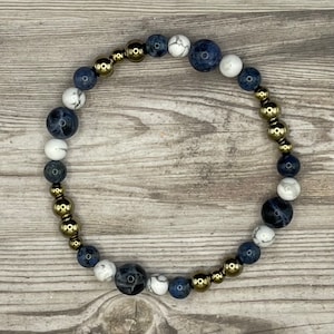 May include: A bracelet made with blue and white beads and gold-toned metal beads.