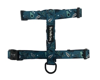 May include: A teal blue dog harness with a white and green avocado print. The harness has a black adjustable buckle and a black metal D-ring. The text "The Crafty Dog" is printed on the harness.