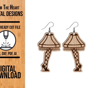 May include: Wooden earrings in the shape of a leg lamp, with a light brown lampshade and a dark brown leg. The earrings have silver hooks. The image also includes the text "FROM THE HEART DIGITAL DESIGNS" and "DIGITAL DOWNLOAD".