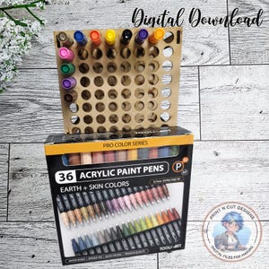 May include: A wooden pen holder with multiple circular openings, holding various coloured markers. Below, a box of 36 acrylic paint pens in earth and skin tones is visible. The box has the text "PRO COLOR SERIES". The image also includes the text "Digital Download".