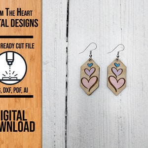 May include: A pair of laser cut wooden earrings with a design of three pink hearts with a blue outline. The earrings are on a white wooden background.  FROM THE HEART DIGITAL DESIGNS LASER READY CUT FILE SVG, DXF, PDF, AI DIGITAL DOWNLOAD