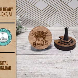 May include: A laser cut wooden car air freshener featuring a Highland Cow design. The air freshener is made of two parts, a round base with a slot for a scent pad and a separate top with the Highland Cow design. The air freshener is ready to be assembled.