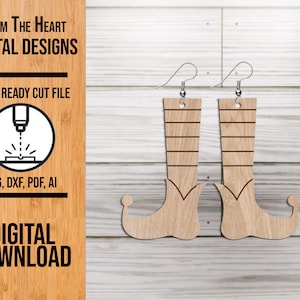 May include: Wooden elf boot earrings with silver-colored hooks. The earrings are light brown with etched details, including horizontal lines and a curved toe. The image also includes text: "From The Heart Digital Designs", "Laser Ready Cut File", and "Digital Download".