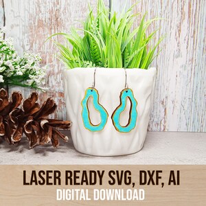 May include: A pair of turquoise blue and gold earrings with a unique organic shape. The earrings are hanging from a white ceramic planter with green plants. The text "LASER READY SVG, DXF, AI DIGITAL DOWNLOAD" is at the bottom of the image.