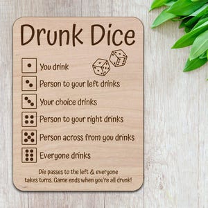 以下が含まれることがあります： 「Drunk Dice」というタイトルの、木製ゲームボードと飲みゲームのルール。ルールには、サイコロの組み合わせと、出た目によって誰が飲むかが書かれている。ボードは薄い茶色で、濃い茶色の文字が書かれている。