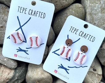 May include: Two pairs of baseball-themed earrings on white cards with the text "TEPE CRAFTED" and the Instagram handle "@tepecrafted". The earrings are made of white clay with red stitching and brown wooden posts.