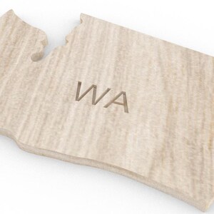 May include: A wooden cutout of the state of Washington with the abbreviation "WA" carved into the surface.