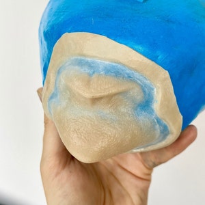 Könnte beinhalten: Nahaufnahme einer beigefarbenen Silikonform eines menschlichen Mundes mit blauer Farbe an den Rändern. Die Form wird von einer Hand gehalten.