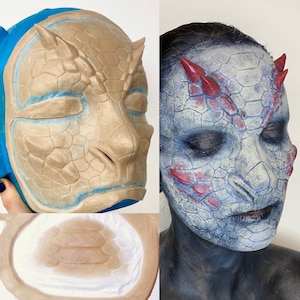 Peut inclure: Image en deux parties montrant un masque de dragon beige et un visage peint en dragon. Le masque est beige avec des détails bleus et des cornes. Le visage est peint avec des écailles bleues, rouges et blanches, et des cornes rouges.